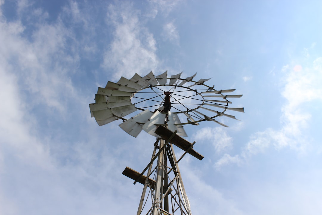 white and black windmill under white clouds and blue sky during daytime